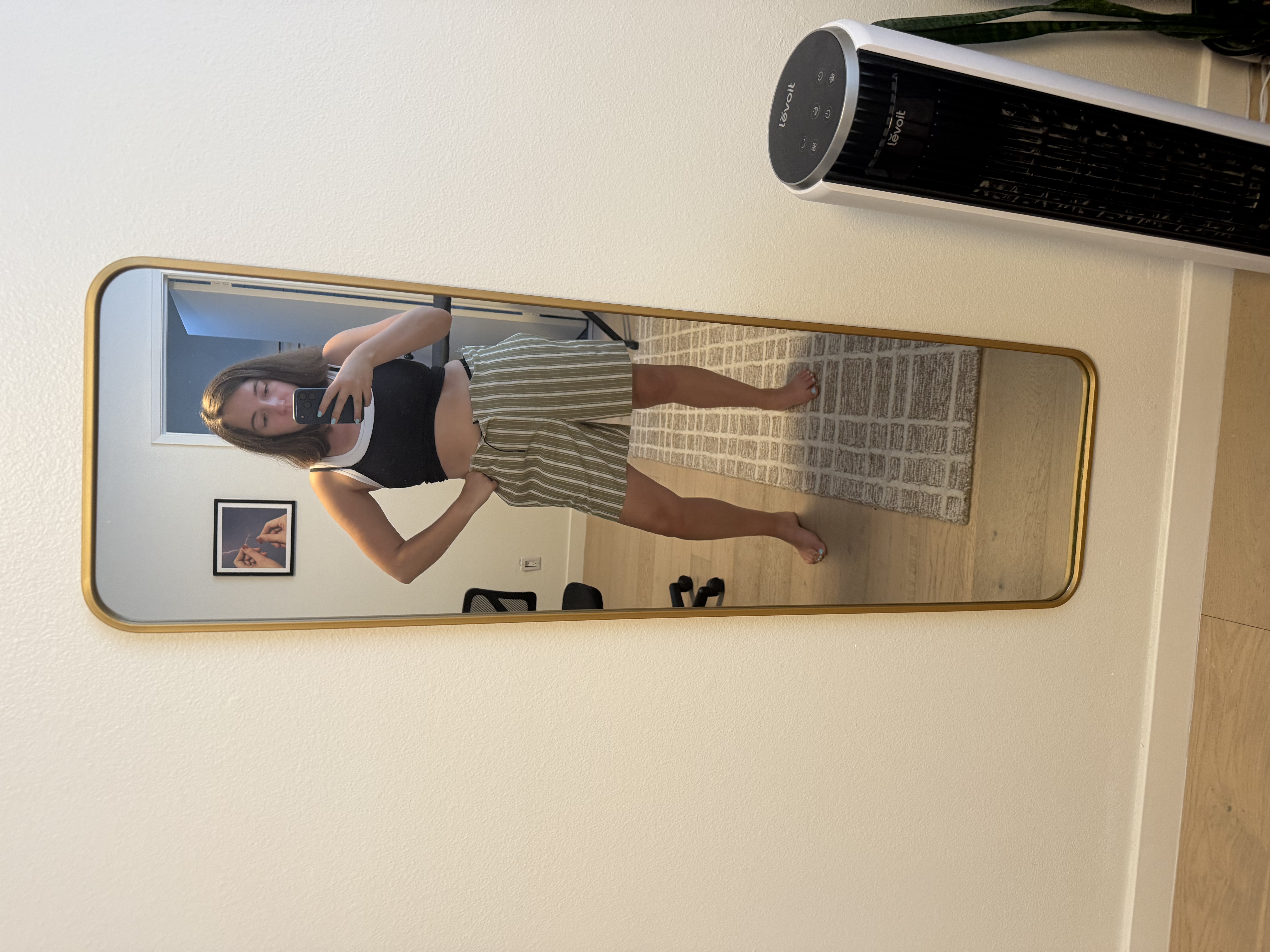 Emily trying on the finished shorts in the mirror before giving them to Chris